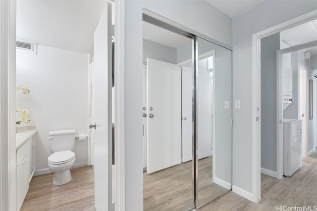 bathroom featuring vanity, wood-type flooring, toilet, and stacked washing maching and dryer