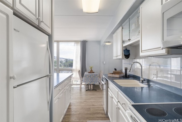 kitchen featuring tasteful backsplash, white cabinetry, sink, and white appliances