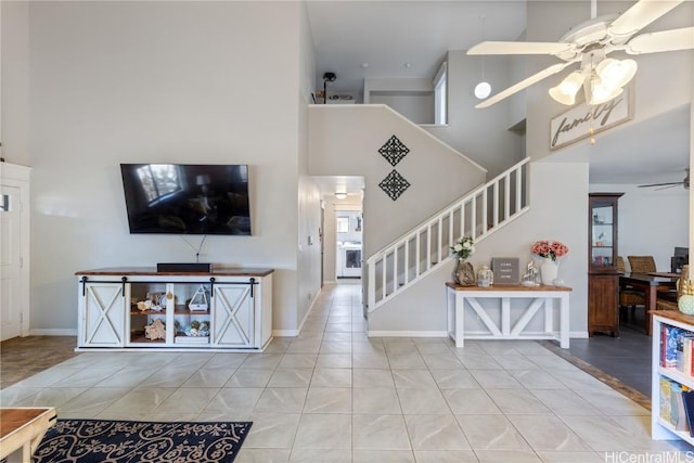 living room with light tile patterned flooring, a towering ceiling, and ceiling fan