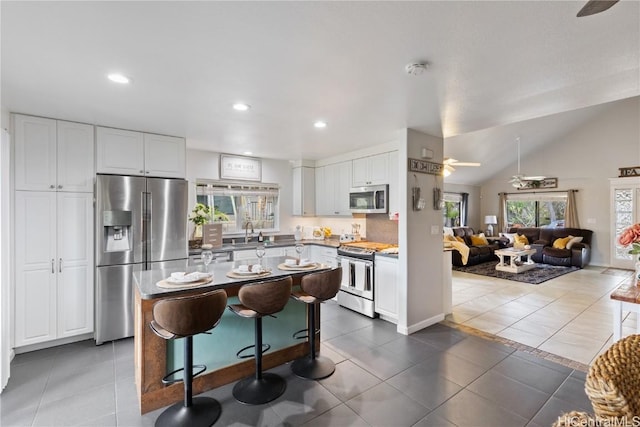 kitchen with white cabinets, a kitchen breakfast bar, tile patterned flooring, a center island, and stainless steel appliances