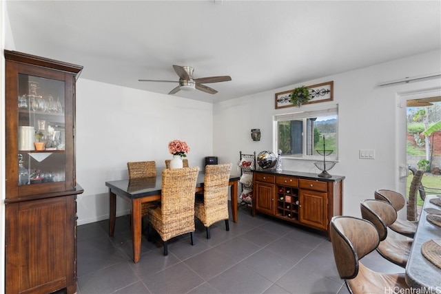 dining area with ceiling fan and dark tile patterned floors