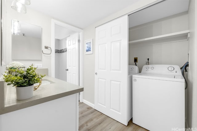 laundry room featuring laundry area, washing machine and clothes dryer, a sink, and light wood-style flooring