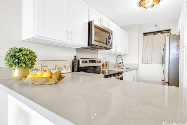 kitchen with white cabinetry, stainless steel appliances, a sink, and light countertops