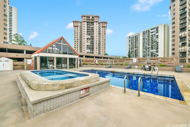 view of pool with a hot tub and a patio