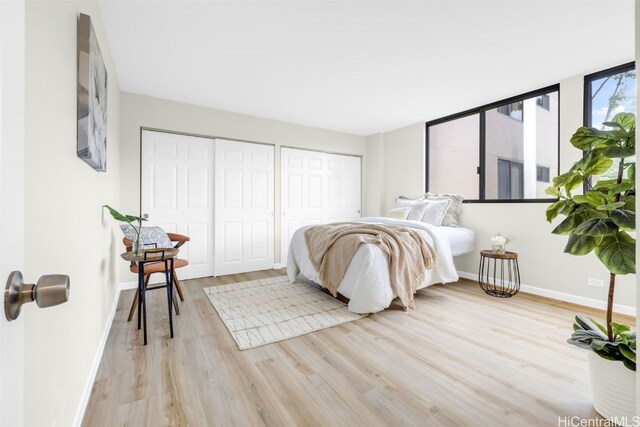 bedroom with two closets and light hardwood / wood-style floors