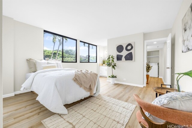 bedroom with light wood-type flooring, washer / clothes dryer, and baseboards