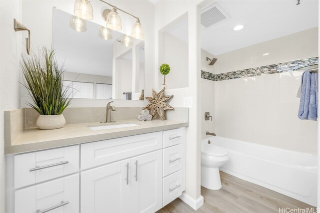 full bathroom with tiled shower / bath combo, wood-type flooring, vanity, and toilet