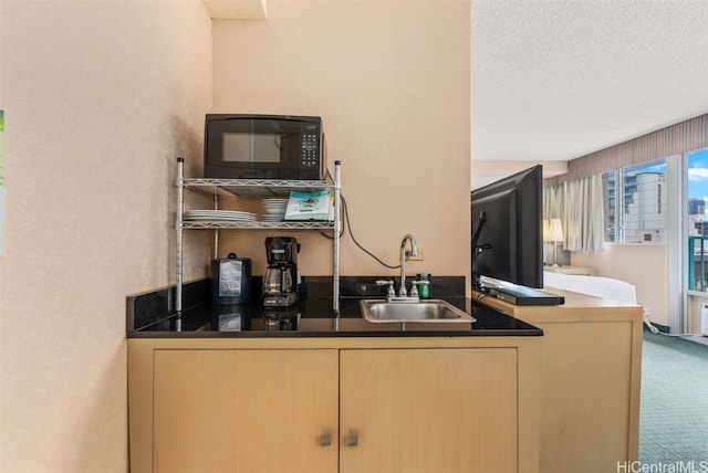 kitchen with light brown cabinets, sink, carpet, and a textured ceiling