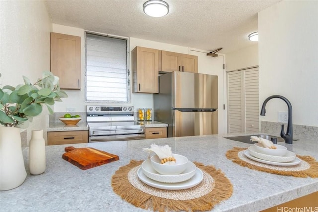 kitchen featuring light brown cabinetry, sink, a textured ceiling, and appliances with stainless steel finishes