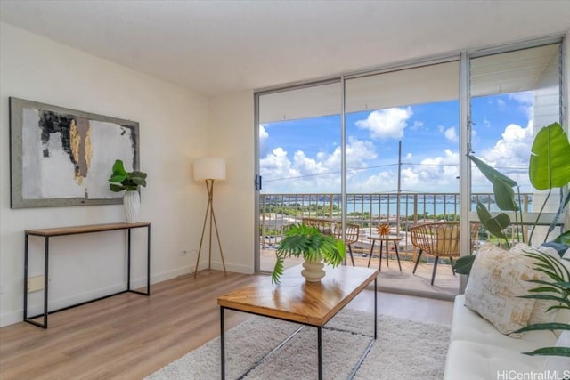 living room featuring a water view, expansive windows, and hardwood / wood-style floors