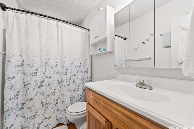 bathroom with toilet, vanity, and a textured ceiling