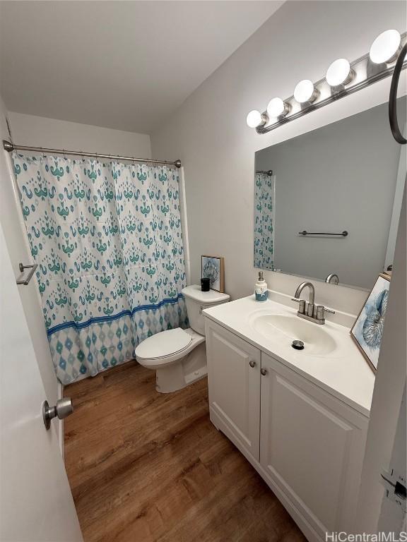 bathroom featuring toilet, vanity, a shower with shower curtain, and wood finished floors