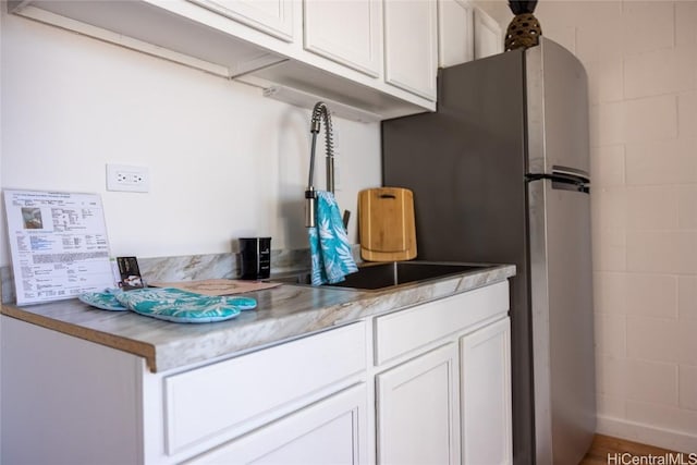 kitchen featuring white cabinets and concrete block wall