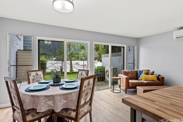 dining room with light hardwood / wood-style flooring and a wall unit AC