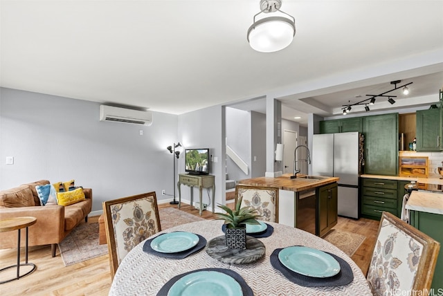 dining room with sink, a wall unit AC, and light hardwood / wood-style floors