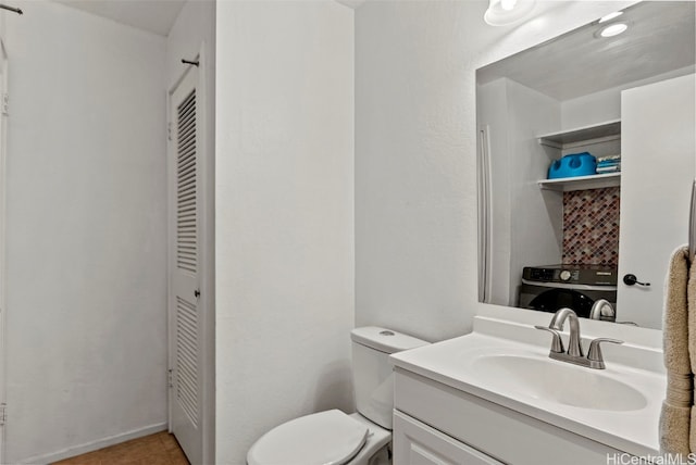 bathroom with vanity, toilet, and washer / dryer