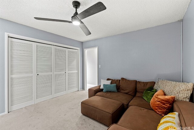 carpeted living room with ceiling fan and a textured ceiling