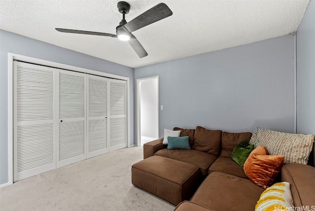 carpeted living room featuring ceiling fan and a textured ceiling