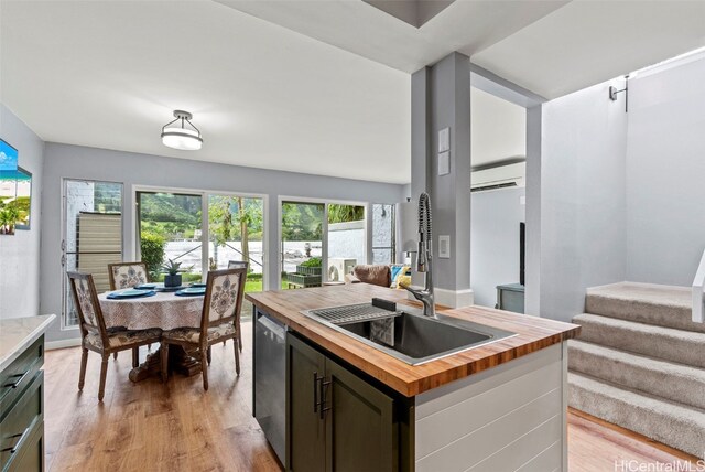 kitchen featuring sink, butcher block countertops, light hardwood / wood-style flooring, a kitchen island with sink, and stainless steel dishwasher