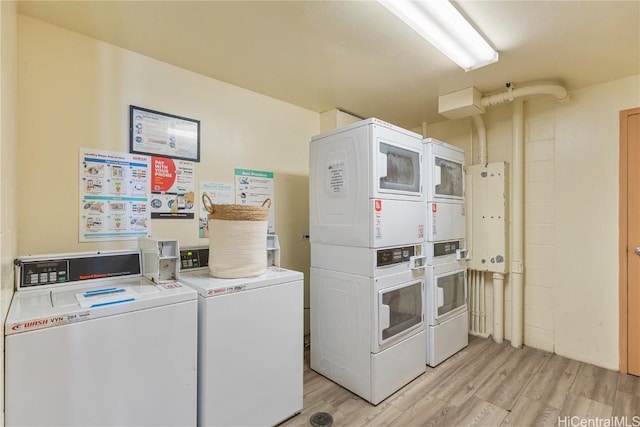 washroom with washing machine and clothes dryer, stacked washing maching and dryer, water heater, and light wood-type flooring