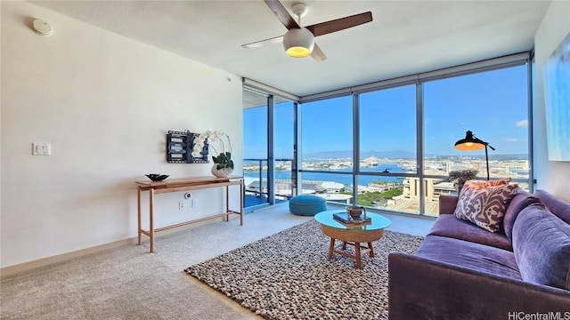 carpeted living room with expansive windows, ceiling fan, and a water view