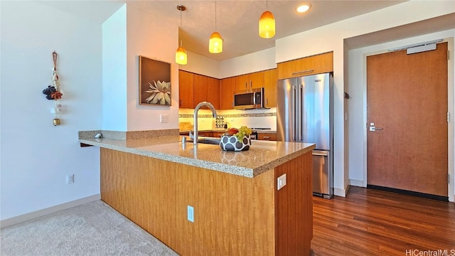 kitchen featuring pendant lighting, sink, appliances with stainless steel finishes, backsplash, and kitchen peninsula