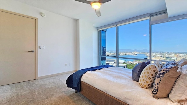 carpeted bedroom with a water view, ceiling fan, and floor to ceiling windows