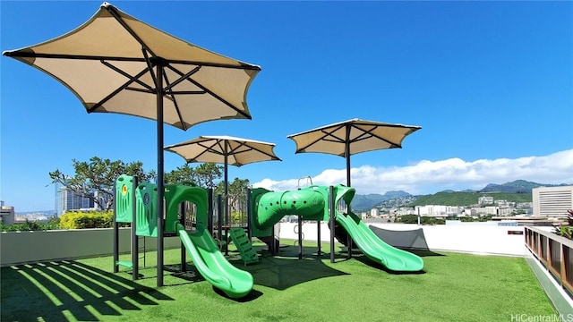 view of jungle gym featuring a mountain view and a lawn