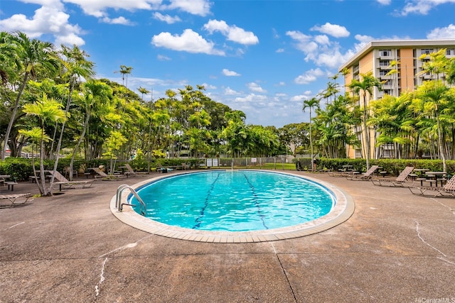 community pool featuring a patio and view of wooded area