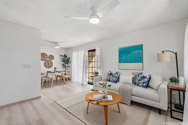 living room with ceiling fan, a textured ceiling, and light hardwood / wood-style floors