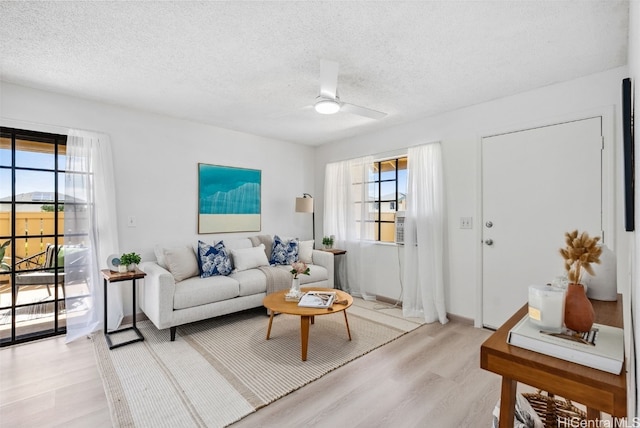 living room with ceiling fan, light hardwood / wood-style floors, and a textured ceiling