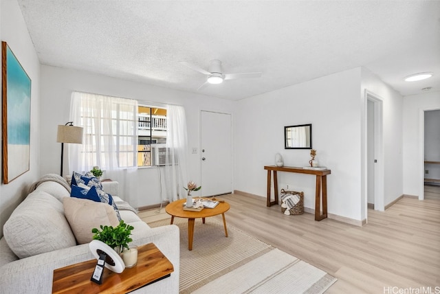 living room featuring ceiling fan, light hardwood / wood-style flooring, and a textured ceiling