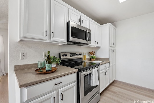 kitchen featuring appliances with stainless steel finishes, white cabinets, and light wood-type flooring