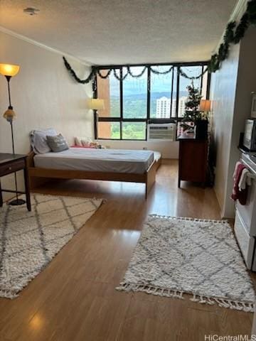 bedroom featuring crown molding, a textured ceiling, and light wood-type flooring