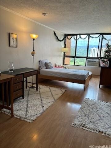 bedroom with crown molding, light hardwood / wood-style flooring, and a textured ceiling