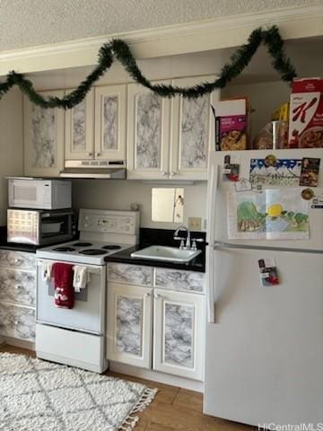 kitchen with sink, white appliances, wood-type flooring, and a textured ceiling