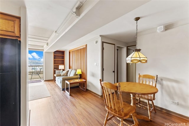 dining room with built in shelves and light hardwood / wood-style floors