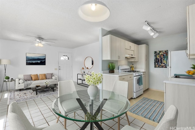 kitchen with track lighting, ceiling fan, white appliances, and a textured ceiling