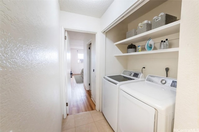 washroom featuring light tile patterned floors, a textured ceiling, and washing machine and clothes dryer