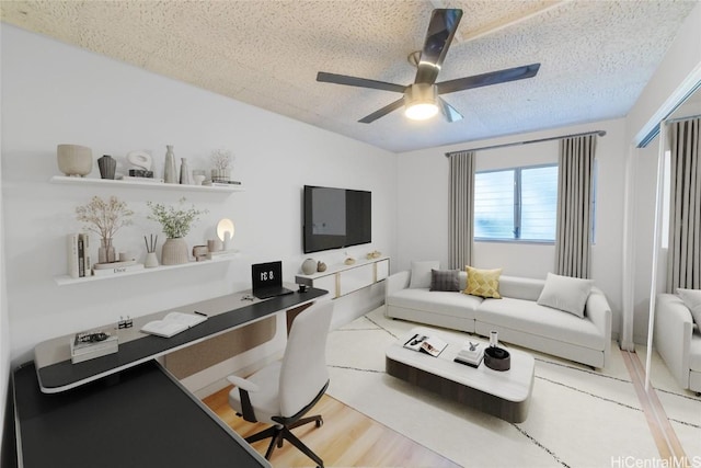 living room with ceiling fan, hardwood / wood-style flooring, and a textured ceiling