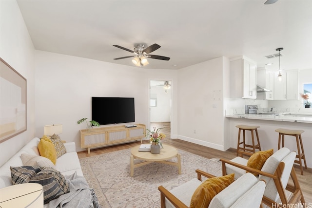 living room with ceiling fan and light hardwood / wood-style flooring