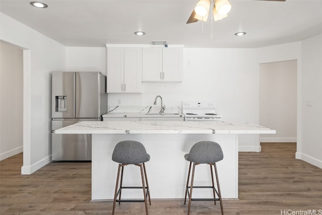 kitchen with sink, white electric range, stainless steel fridge, a center island, and white cabinets