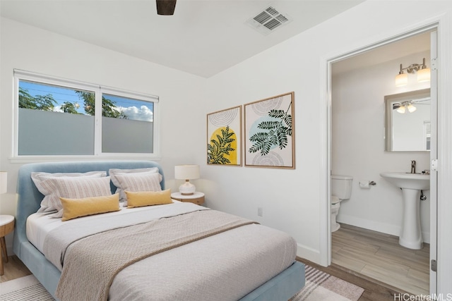 bedroom with ensuite bathroom, ceiling fan, and light wood-type flooring