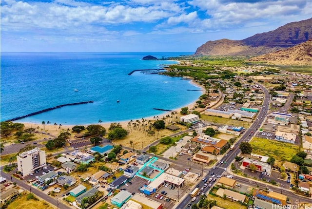 drone / aerial view with a water and mountain view and a beach view