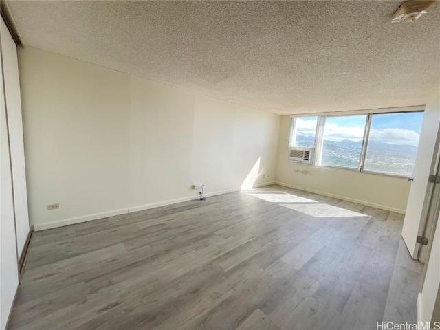 unfurnished room with hardwood / wood-style floors and a textured ceiling