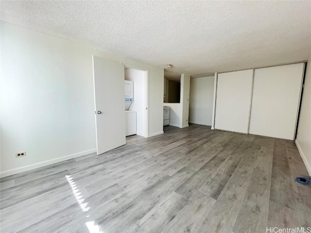 unfurnished bedroom featuring a textured ceiling, light wood-type flooring, and a closet