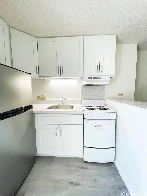 kitchen featuring sink, white electric range oven, white cabinets, and stainless steel refrigerator