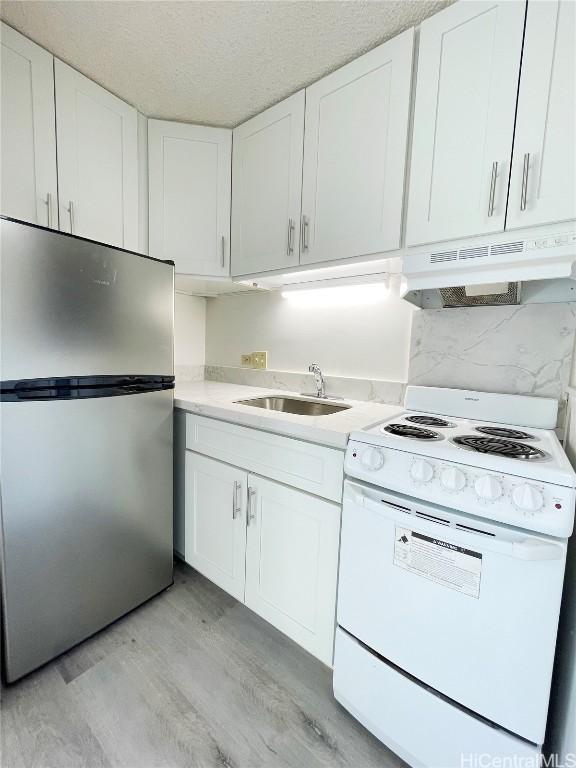 kitchen featuring sink, light hardwood / wood-style flooring, stainless steel refrigerator, white range with electric cooktop, and white cabinetry