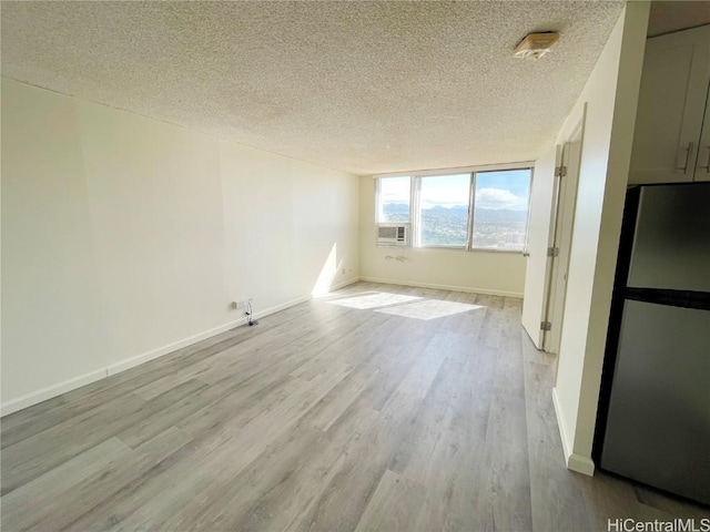 unfurnished room featuring a textured ceiling and light wood-type flooring