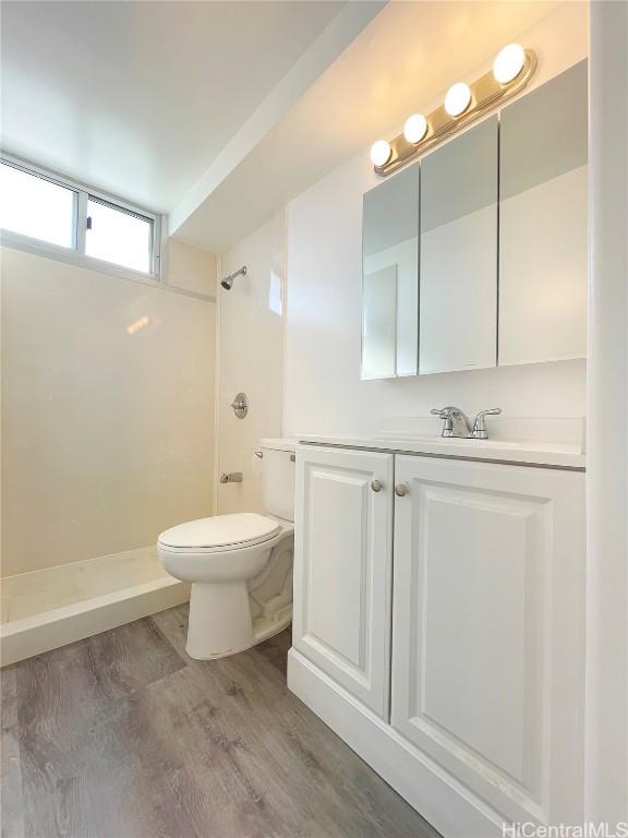 bathroom featuring vanity, wood-type flooring, toilet, and a shower